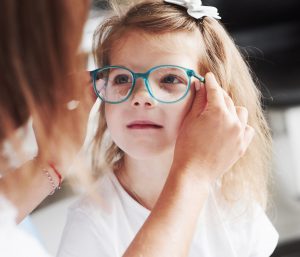 Young girl getting glasses placed on face